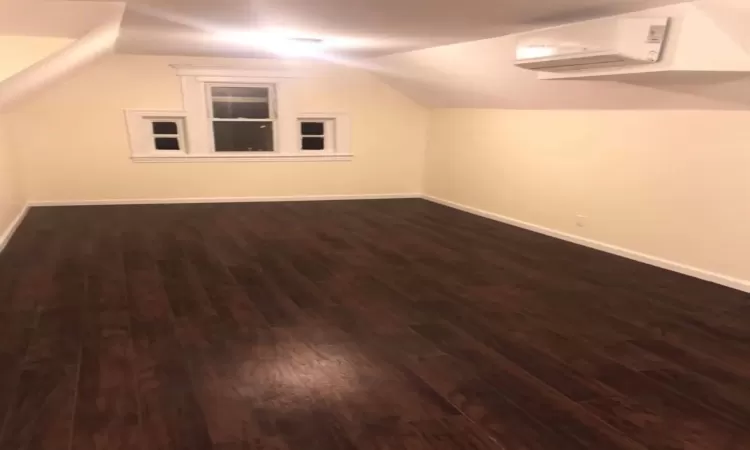 Additional living space with dark wood-type flooring and lofted ceiling