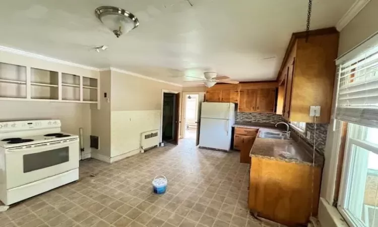 Kitchen featuring radiator, ceiling fan, sink, white appliances, and ornamental molding