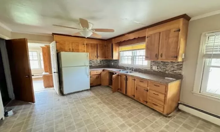 Kitchen with decorative backsplash, white fridge, a baseboard heating unit, and sink