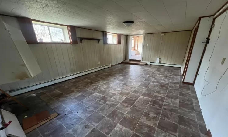 Basement featuring wooden walls and a baseboard radiator