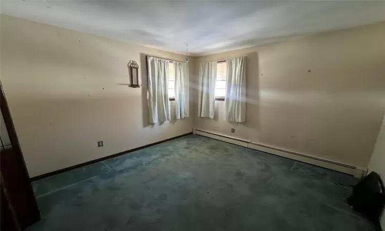 Empty room with dark carpet and baseboard heating