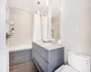 Full bathroom featuring toilet, vanity, shower / tub combo with curtain, and tile walls