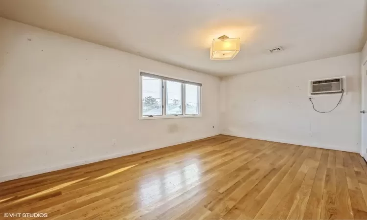 Empty room with light hardwood / wood-style floors and a wall mounted AC