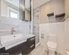 Bathroom with vanity, toilet, walk in shower, and tile walls