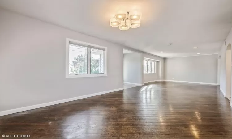 Unfurnished room featuring a chandelier and dark hardwood / wood-style flooring