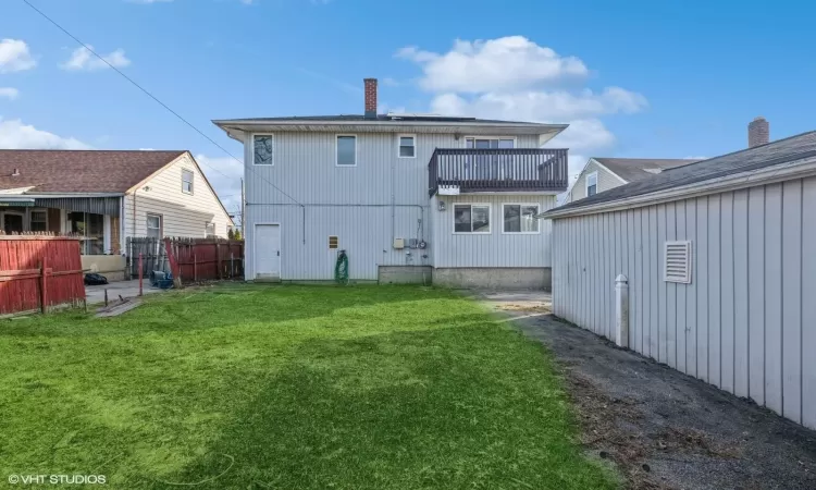 Back of property featuring a balcony and a yard