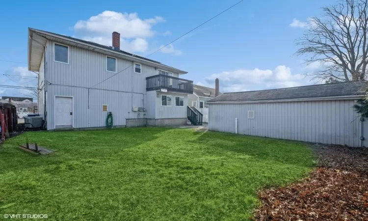 Rear view of property featuring a balcony, a yard, and central air condition unit