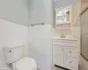 Full bathroom with vanity, bath / shower combo with glass door, tile walls, and toilet