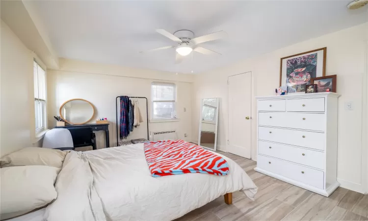 Bedroom with radiator heating unit, light hardwood / wood-style flooring, and ceiling fan