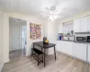 Kitchen with dishwasher, white cabinets, sink, dark stone countertops, and light wood-type flooring