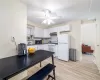 Kitchen with white appliances, ceiling fan, sink, white cabinets, and light hardwood / wood-style floors