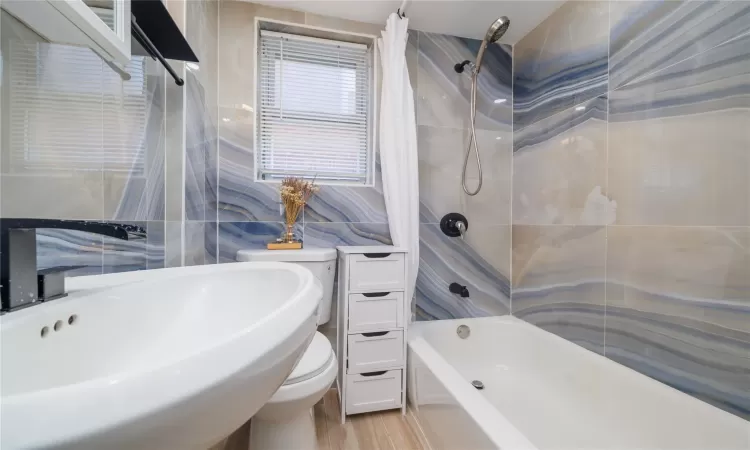 Full bathroom with sink, toilet, tile walls, and shower / tub combo