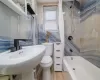 Full bathroom featuring sink, wood-type flooring, shower / bathtub combination with curtain, tile walls, and toilet