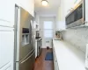 Kitchen with radiator, white cabinets, sink, dark hardwood / wood-style flooring, and stainless steel appliances