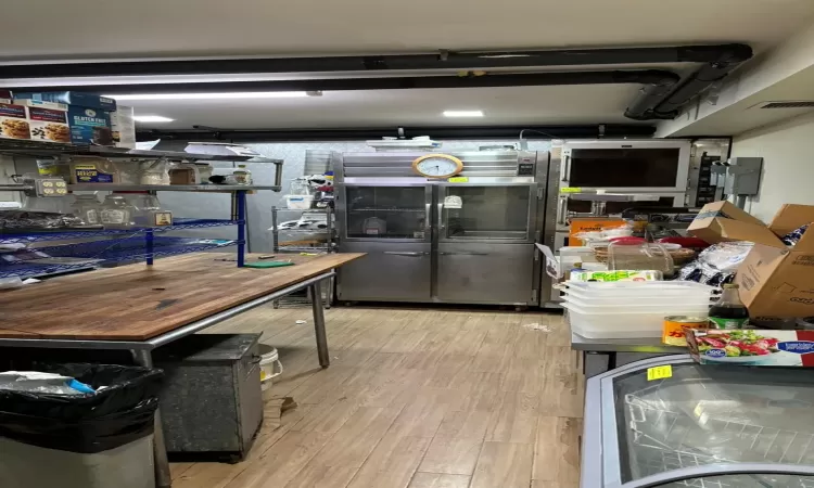 Basement with stainless steel fridge and light hardwood / wood-style flooring