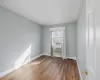 Empty room featuring a wall mounted air conditioner, wood-type flooring, and a baseboard heating unit