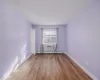 Empty room featuring light hardwood / wood-style floors, a wall unit AC, and a baseboard heating unit