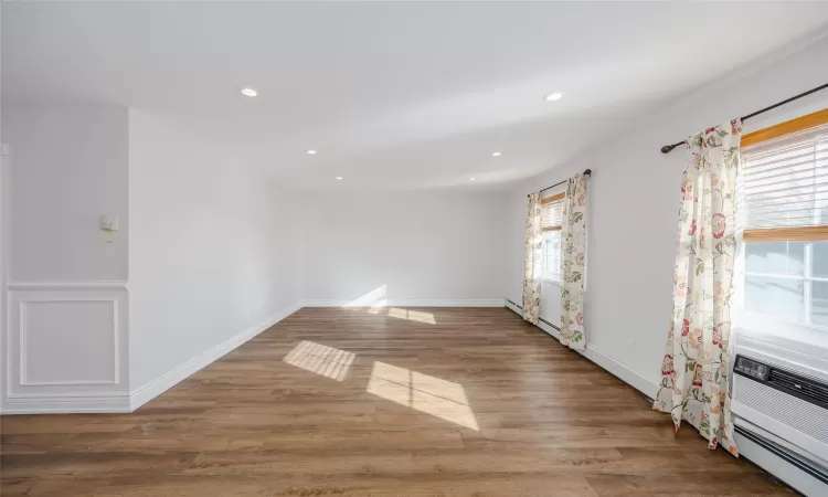 Unfurnished room featuring dark hardwood / wood-style flooring and a baseboard heating unit