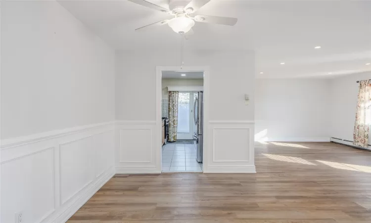 Spare room featuring baseboard heating, ceiling fan, and light hardwood / wood-style floors