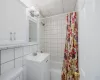 Full bathroom featuring shower / bathtub combination with curtain, toilet, a paneled ceiling, decorative backsplash, and tile walls