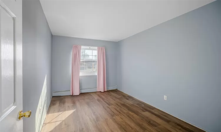 Unfurnished room featuring a baseboard heating unit and light wood-type flooring