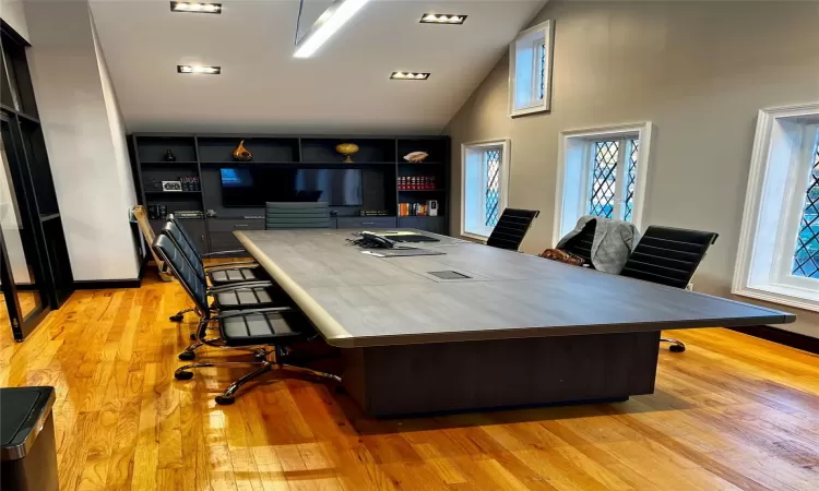 Home office with light hardwood / wood-style floors and high vaulted ceiling