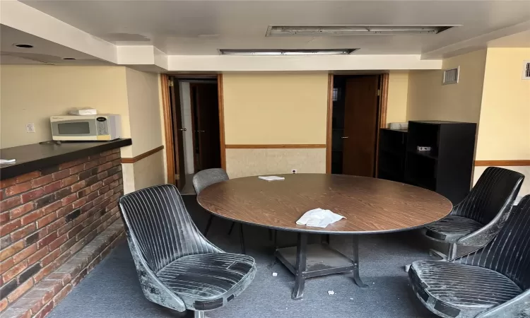 Dining area with dark colored carpet and brick wall