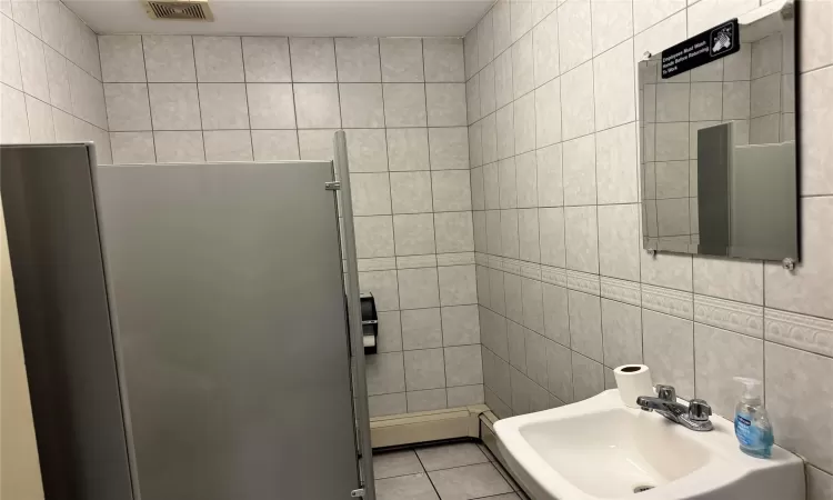 Bathroom with tile patterned floors, tile walls, and sink