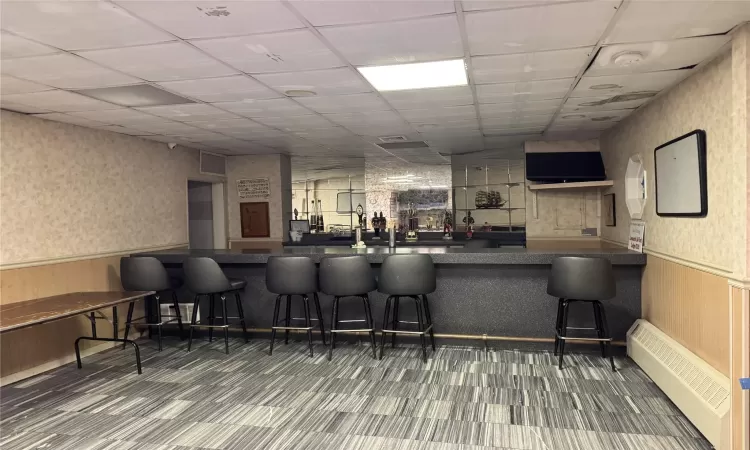 Bar featuring a paneled ceiling and a baseboard radiator