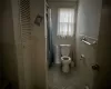 Bathroom with toilet, tile patterned floors, tile walls, and curtained shower