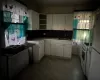 Kitchen with a wealth of natural light, white cabinetry, sink, and white appliances