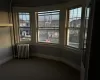 Carpeted empty room featuring a wealth of natural light and radiator