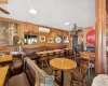 Carpeted dining room with a wall mounted air conditioner, ceiling fan, wood walls, and decorative columns