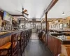 Bar with plenty of natural light, dark hardwood / wood-style floors, ceiling fan, and decorative columns