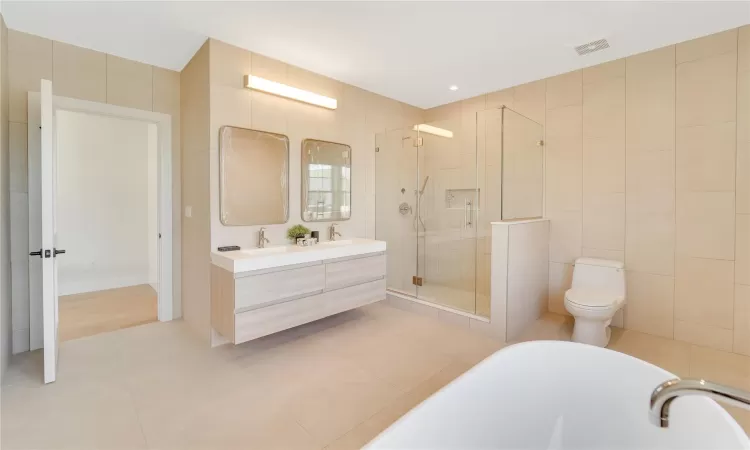 Full bathroom with vanity, tile patterned floors, separate shower and tub, toilet, and tile walls