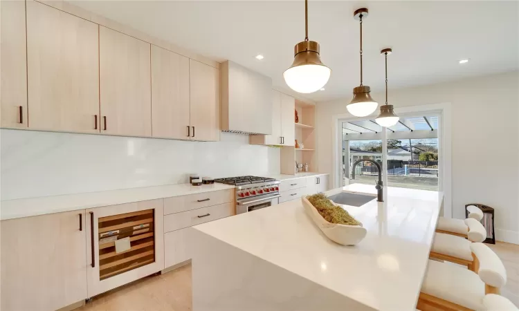 Kitchen featuring light brown cabinets, sink, luxury stove, and light hardwood / wood-style flooring