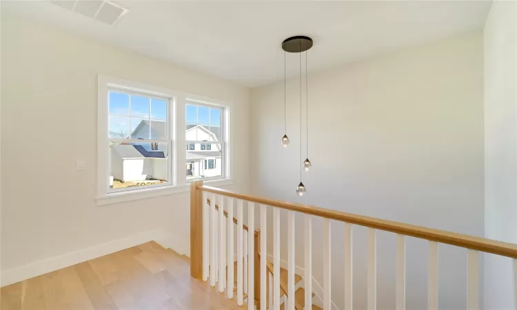 Living area with light wood-type flooring, a fireplace, a towering ceiling, and baseboards