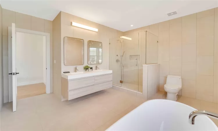 Full bathroom with tile patterned flooring, vanity, toilet, and tile walls