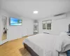 Bedroom featuring hardwood / wood-style floors, radiator heating unit, and an AC wall unit