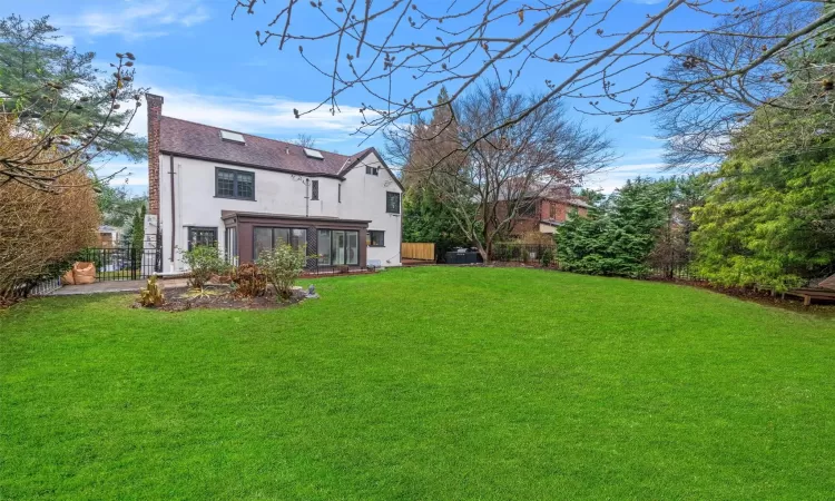 Back of property with a sunroom and a lawn