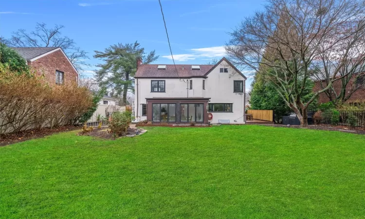 Back of house with a yard and a sunroom