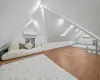 Bonus room with vaulted ceiling with skylight, a wall mounted air conditioner, and wood-type flooring