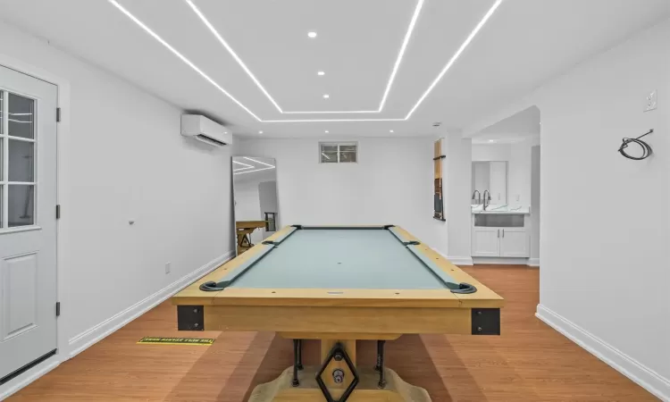 Recreation room featuring a wall mounted air conditioner, wood-type flooring, and pool table