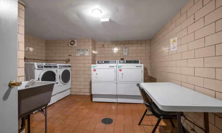 Laundry area with tile walls and washing machine and clothes dryer