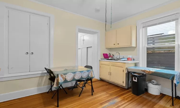 Kitchen with sink, cream cabinetry, light hardwood / wood-style floors, and ornamental molding