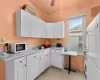 Kitchen featuring ceiling fan, sink, light stone counters, white appliances, and white cabinets