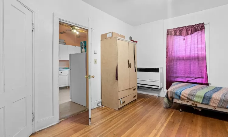 Bedroom featuring white fridge, light hardwood / wood-style flooring, and heating unit