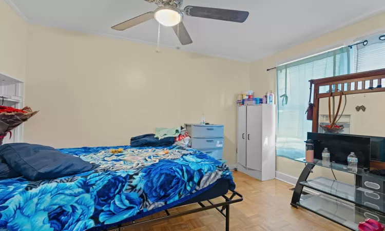 Bedroom featuring light parquet floors, ceiling fan, and crown molding