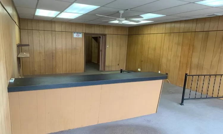 Bar with a paneled ceiling, ceiling fan, and wooden walls