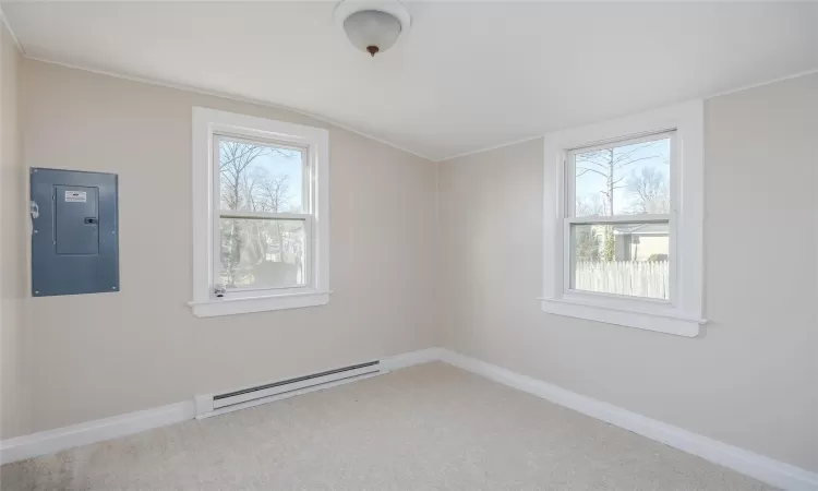 Additional living space featuring electric panel, vaulted ceiling, baseboard heating, and a healthy amount of sunlight